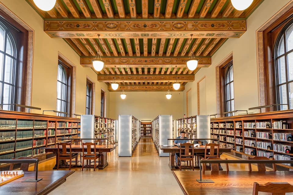 Een bibliotheekinterieur met hoge plafonds, grote ramen en uitgebreide boekencollecties.