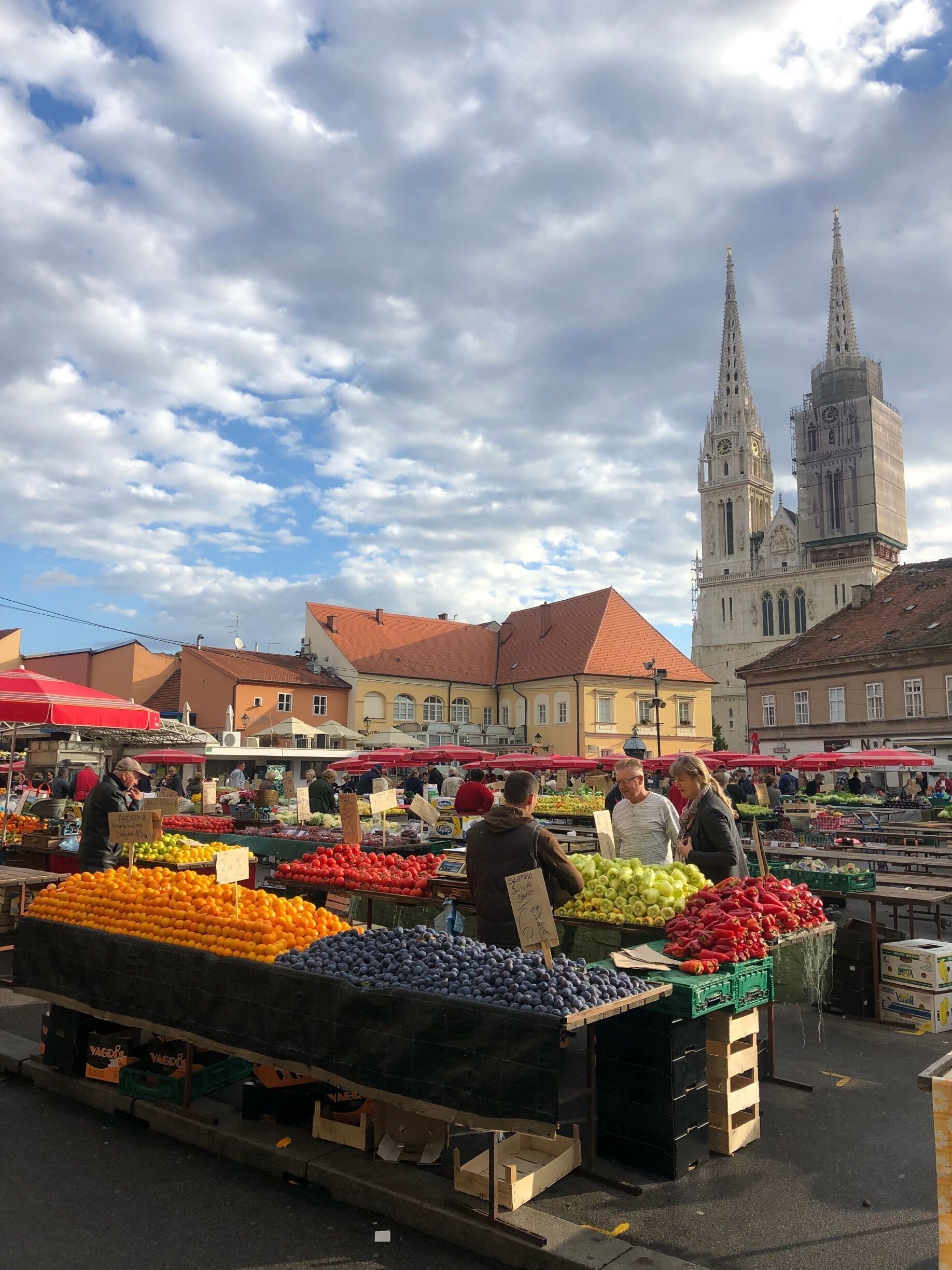 An outdoor market with fresh produce and a historic church in the background.