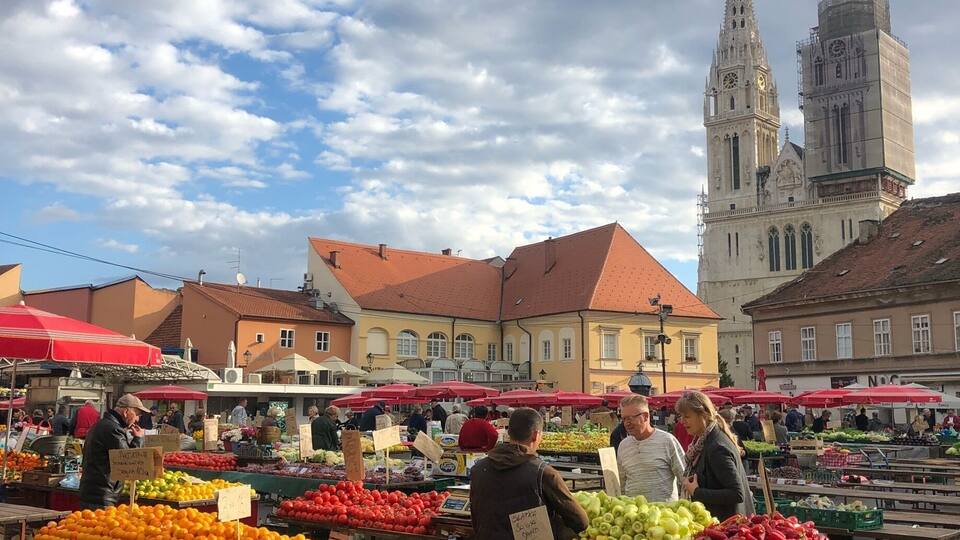 An outdoor market with fresh produce and a historic church in the background.