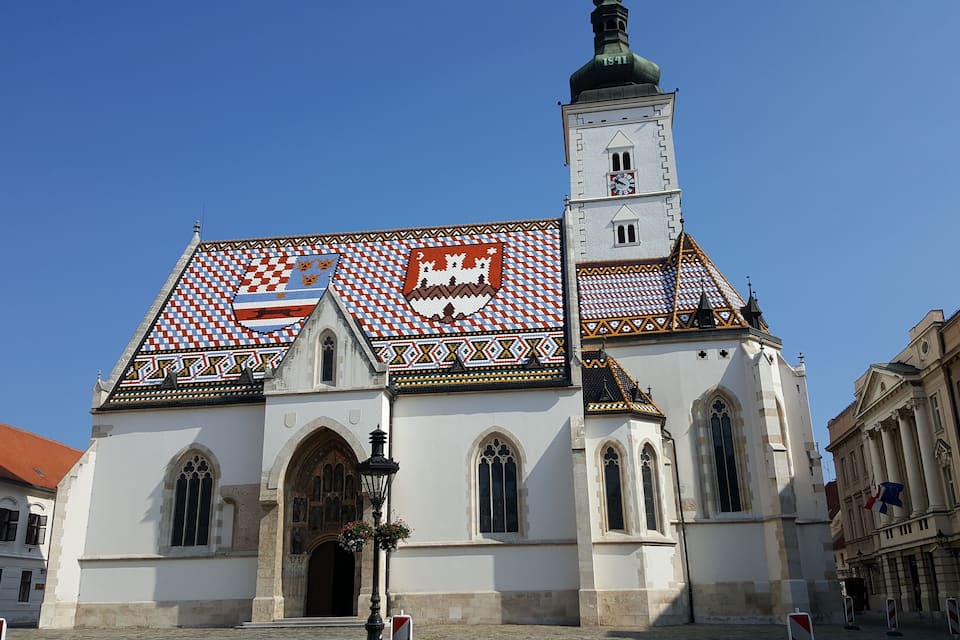 A church with a tiled roof and a clock tower.