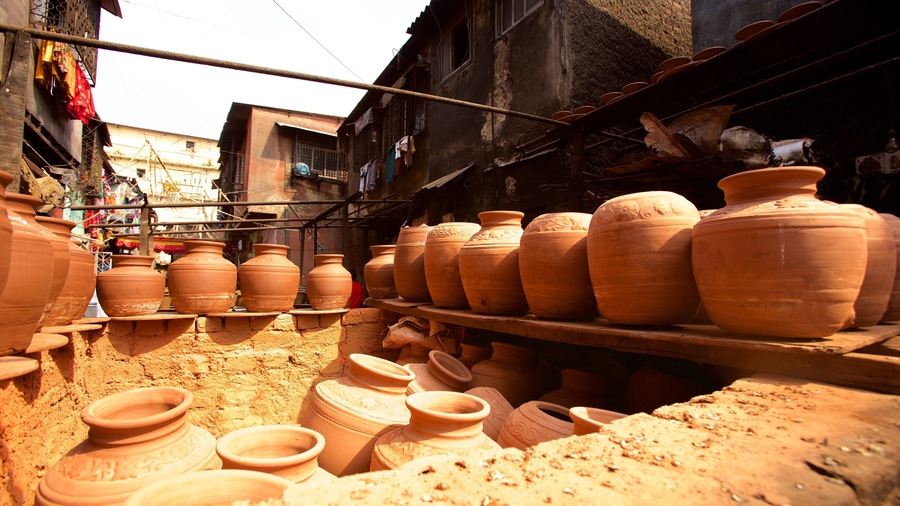 Terracotta pots displayed on shelves in a market setting.