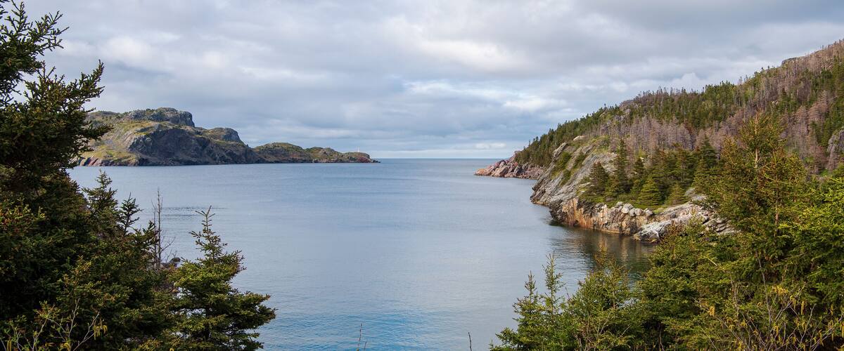 A calm lake surrounded by dense forests and rocky cliffs.