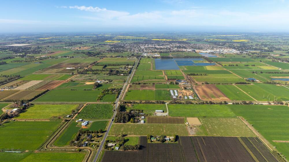 Aerial view of beautiful patchwork farmland and tranquil wetlands under a blue sky, Kyabram, Australia.