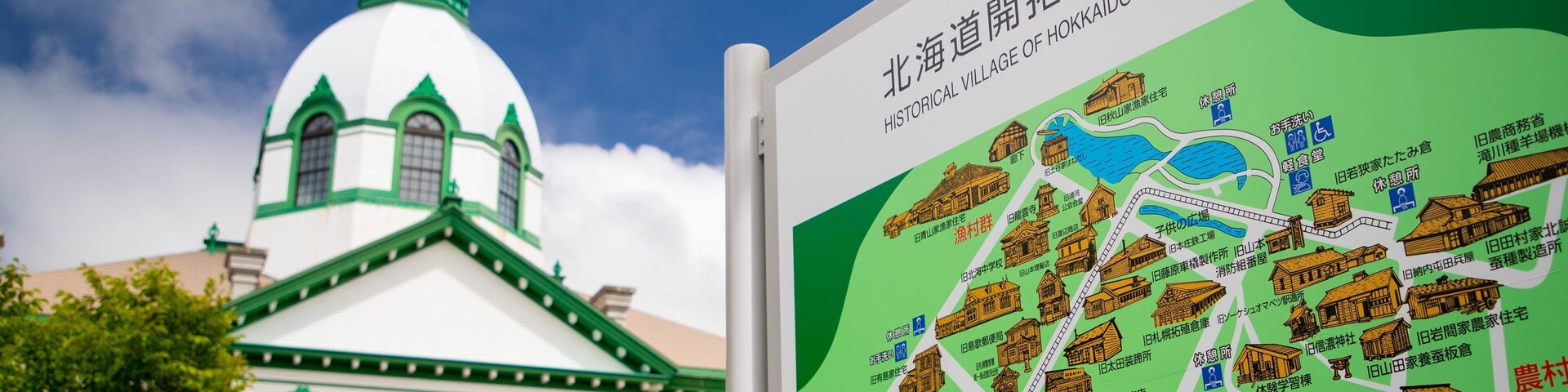 A historical village map with traditional buildings and a large white building with a green dome in the background.