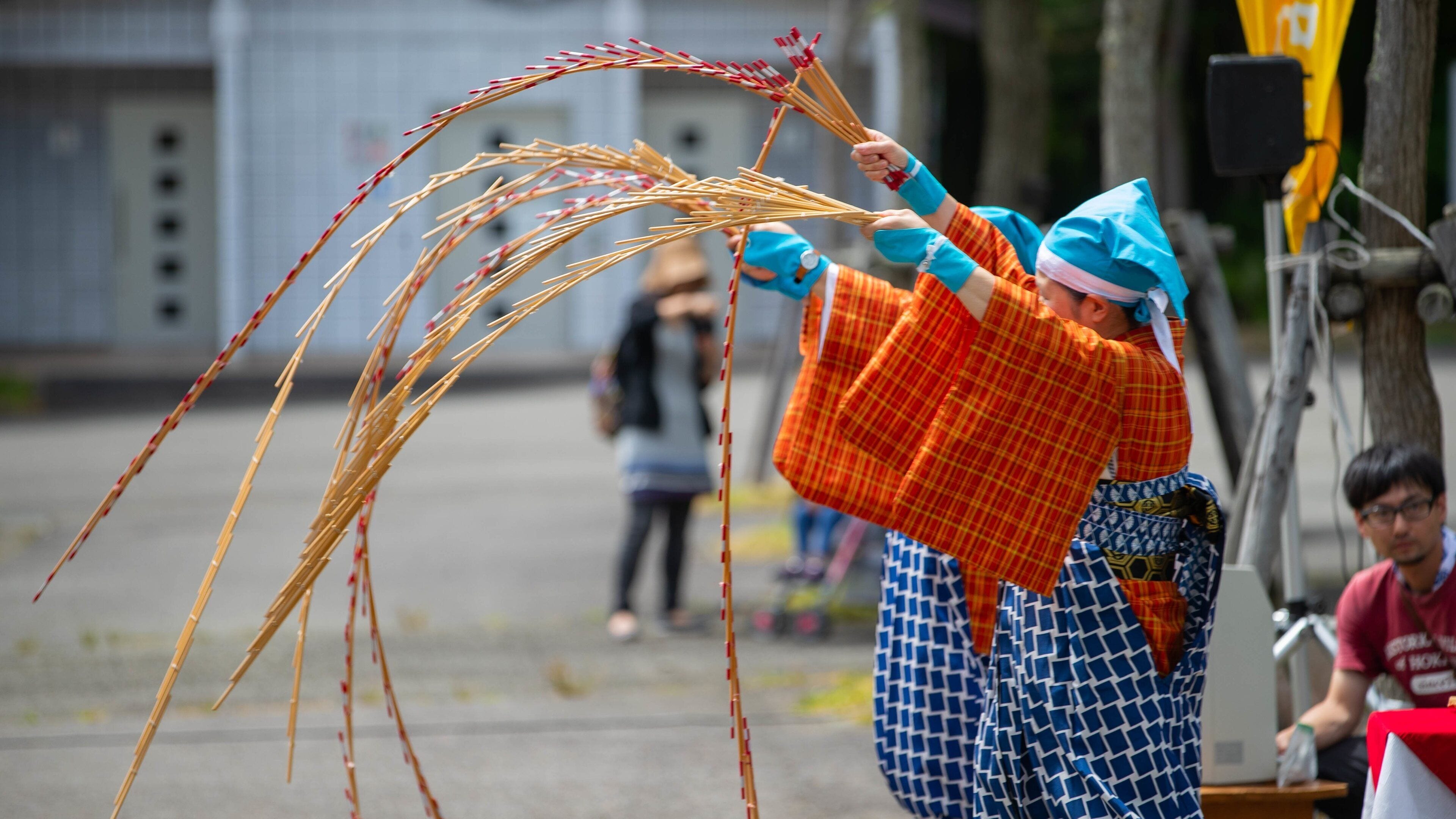 A person in traditional attire holding a long, thin object.