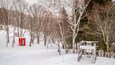 A snowy landscape with a red structure and a white bench.
