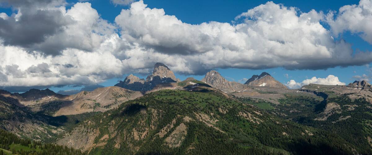 A mountain range with prominent peaks and a clear sky with clouds.