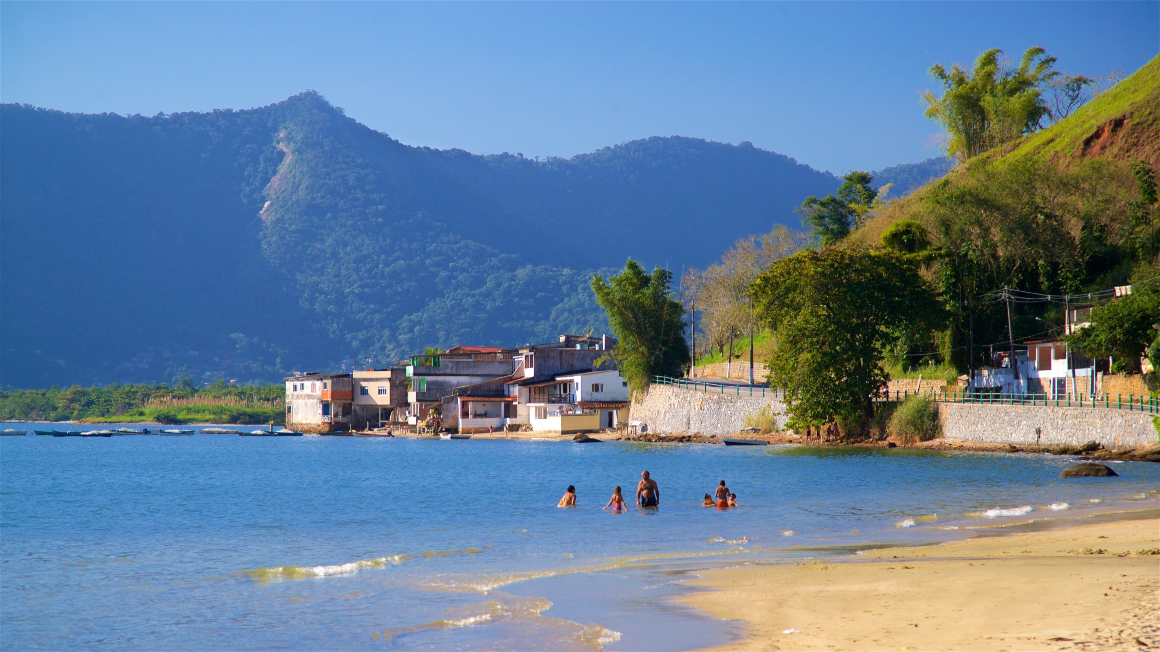 Enseada Beach ofreciendo una playa de arena, una ciudad costera y natación