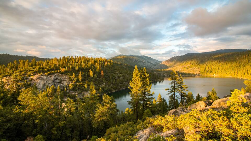 A lake surrounded by dense forest and mountains.