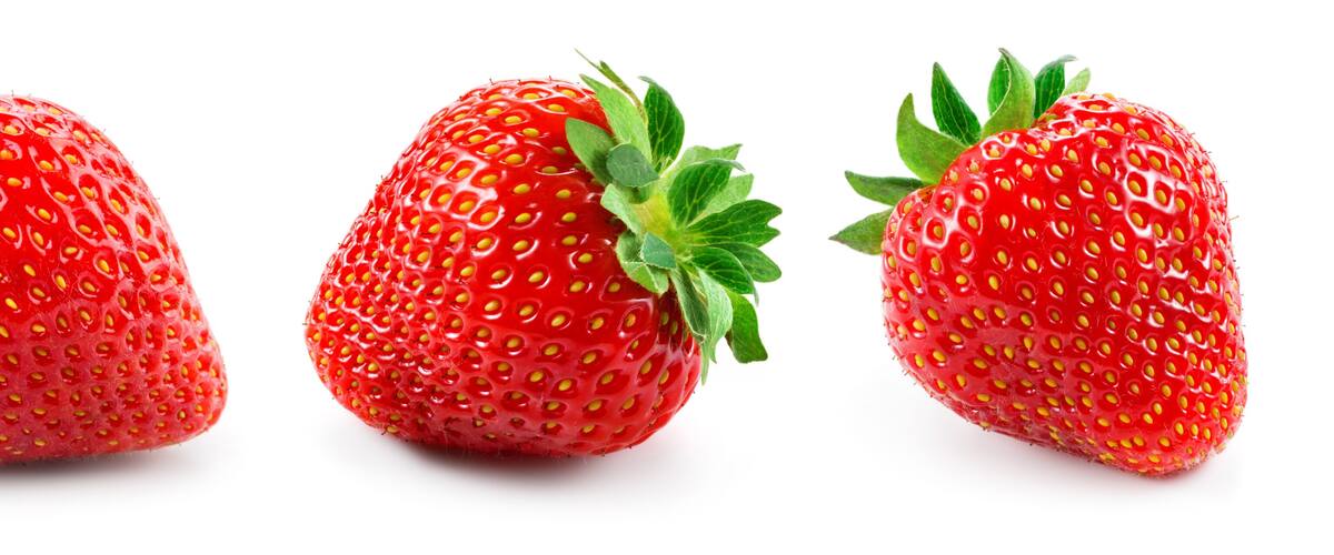 Three strawberries with green leaves.