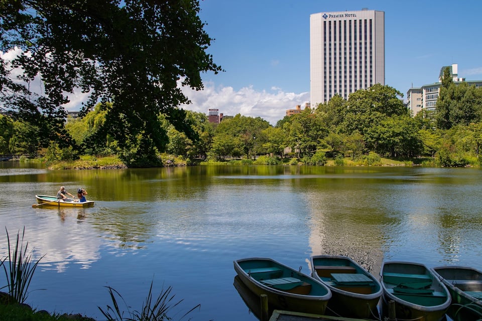A calm lake with boats, a rowboat with two people, and a tall hotel building in the background.