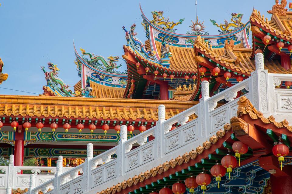 Um edifício tradicional chinês com telhados ricamente decorados, lanternas vermelhas e esculturas detalhadas.