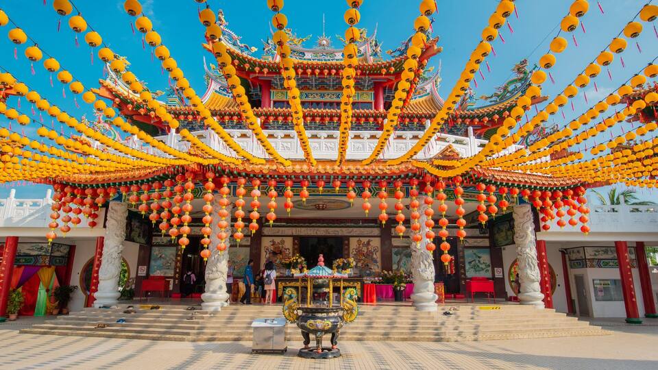 A traditional Chinese temple with ornate architecture, red and yellow lanterns, and a central incense burner.
