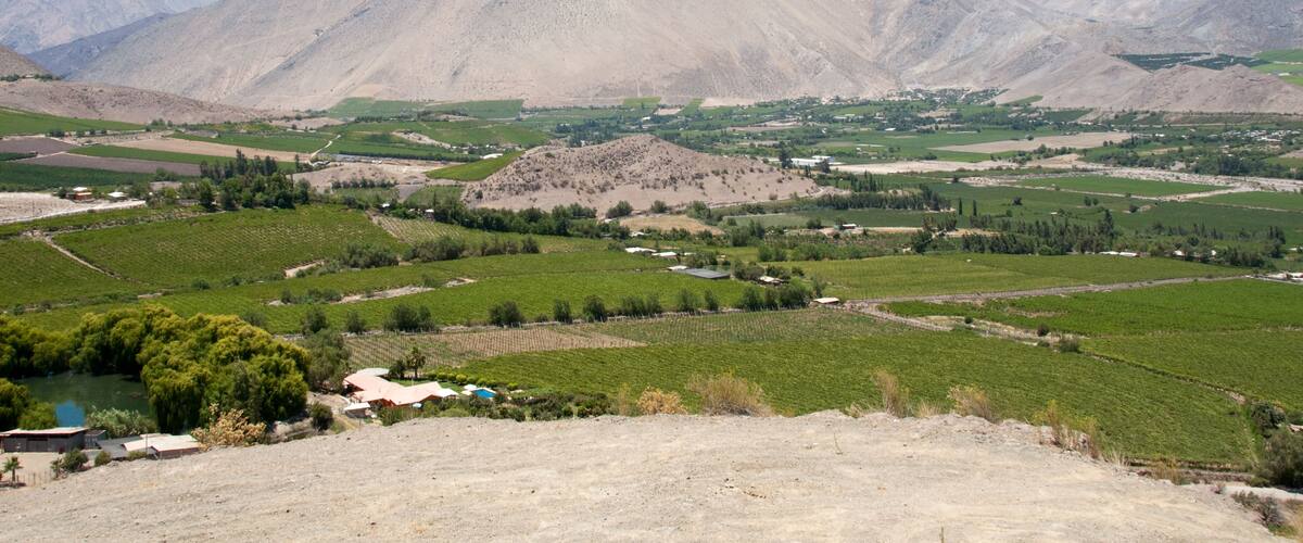 A mountainous landscape with green fields and a small village.