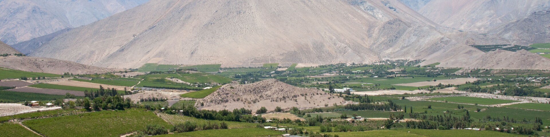 A mountainous landscape with green fields and a small village.