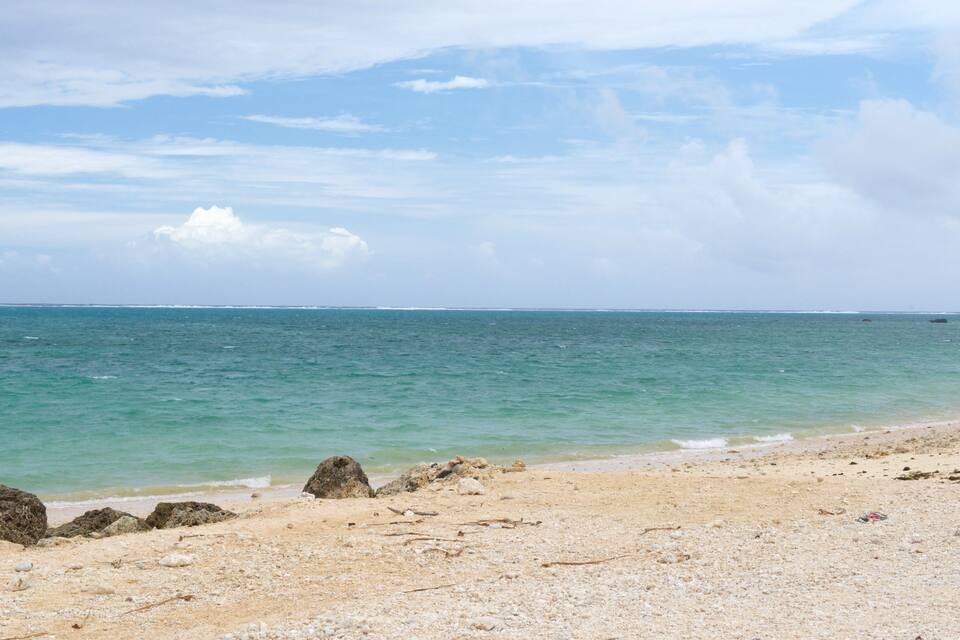 Una playa con agua turquesa cristalina, afloramientos rocosos y una orilla arenosa.