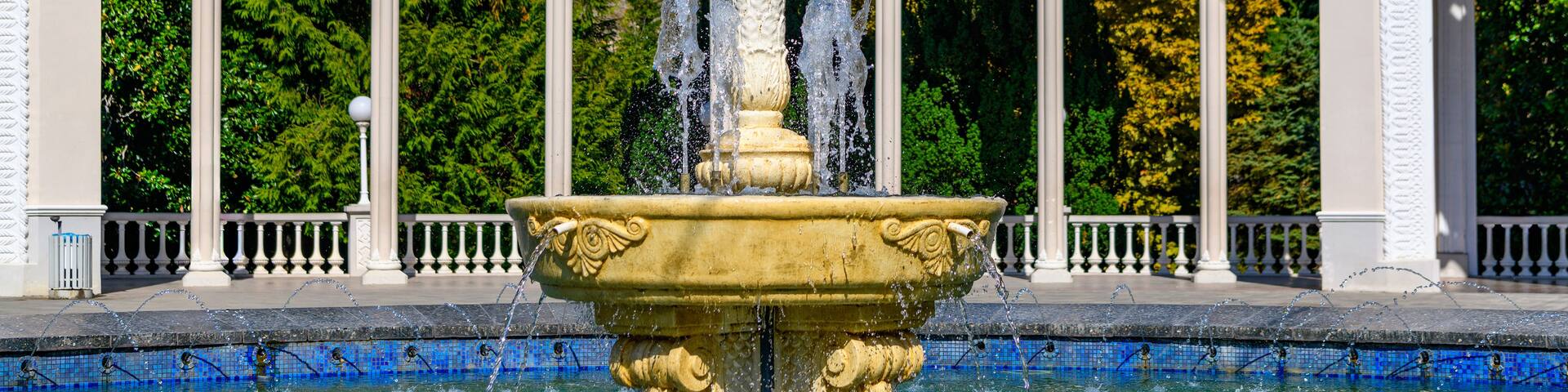 A fountain with a statue of an eagle, surrounded by white columns and a blue-tiled pool.