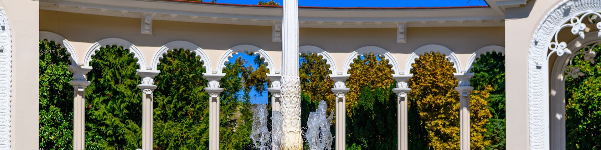 Una fuente con una estatua de un águila, rodeada de columnas blancas y una piscina con azulejos azules.