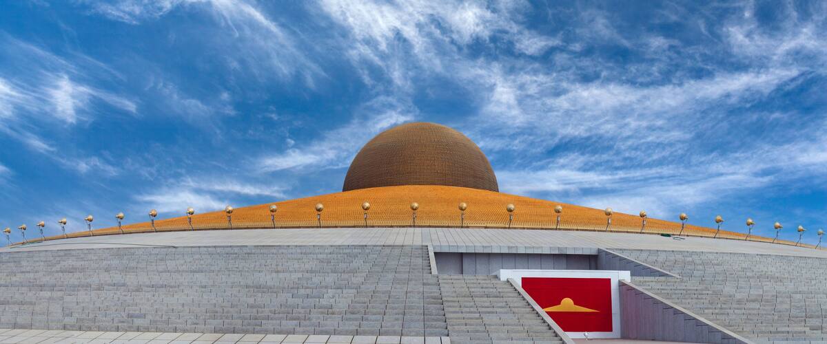 A large, spherical building with a golden roof and a red flag in front.