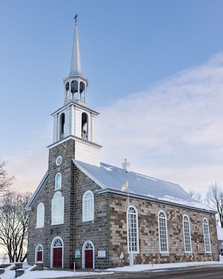 The 1861 small stone Notre-Dame-du-Portage catholic church seen in the quaint Bas-Saint-Laurent region village during a winter dawn, Quebec, Canada