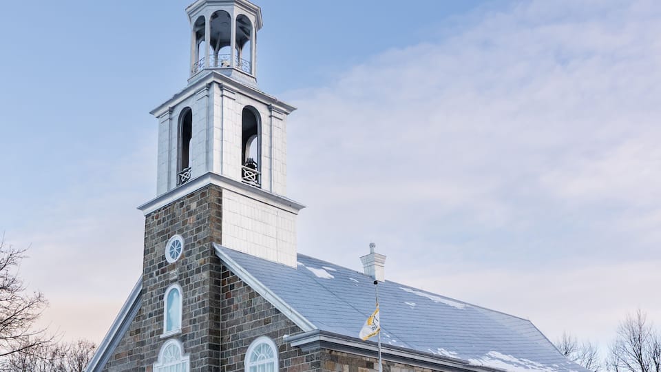 A stone church with a steeple and a bell tower.