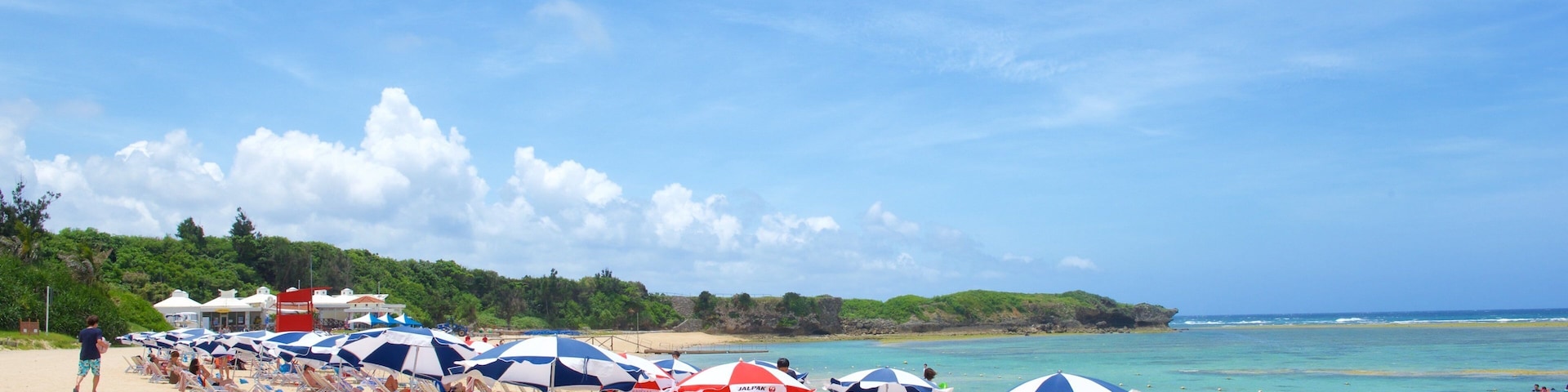 Nirai Beach which includes general coastal views and a sandy beach as well as a large group of people