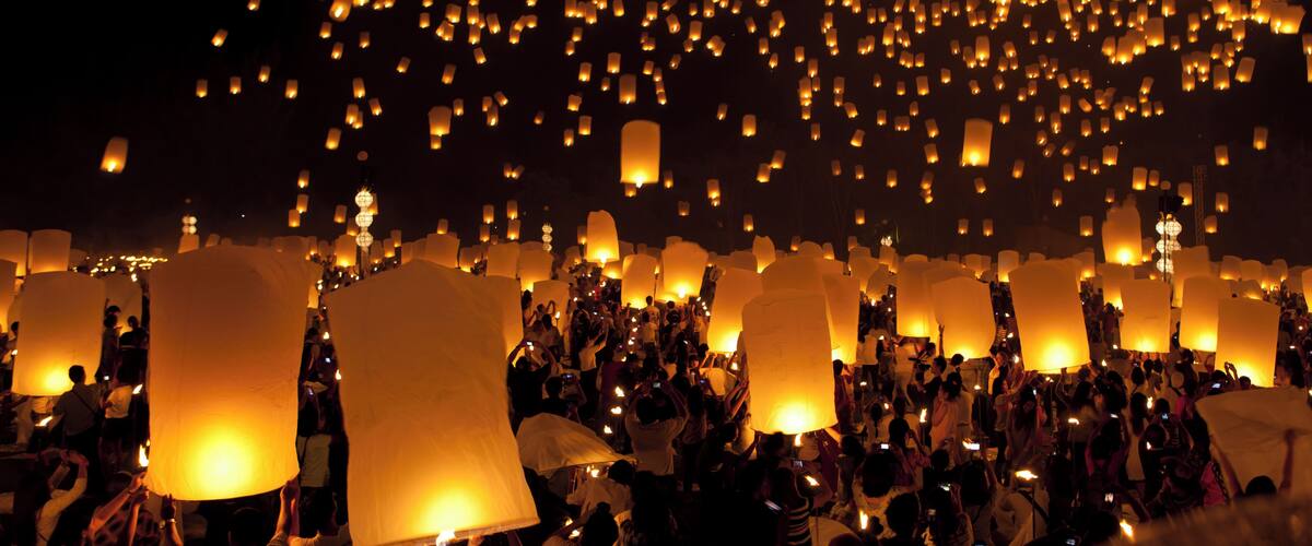 A crowd of people releasing sky lanterns at night.