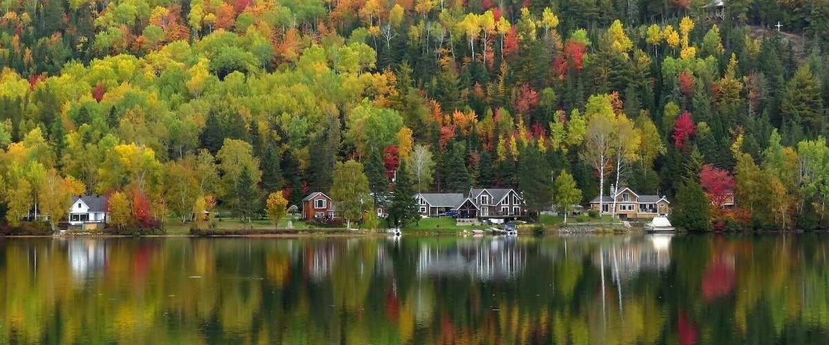 A lake surrounded by autumn-colored trees and houses.