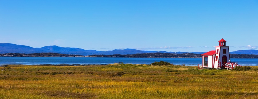 Small red and white lighthouse along the Saint Lawrence River; Saint Andre de Kamourraska, Quebec, Canada
