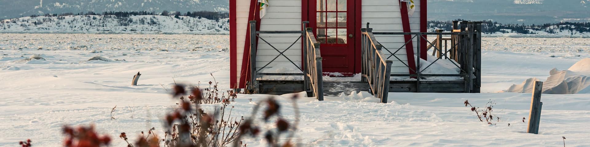 Winter's view of the little lighthouse of Saint-Andre-de-Kamouraska with ice on Saint-Lawrence river and the Charlevoix in background (Quebec, Canada).