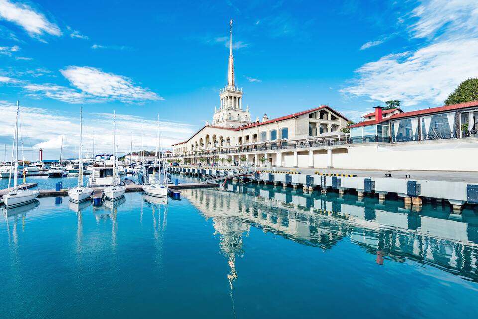 A marina with boats, a large building with a tower, and a clear blue sky.