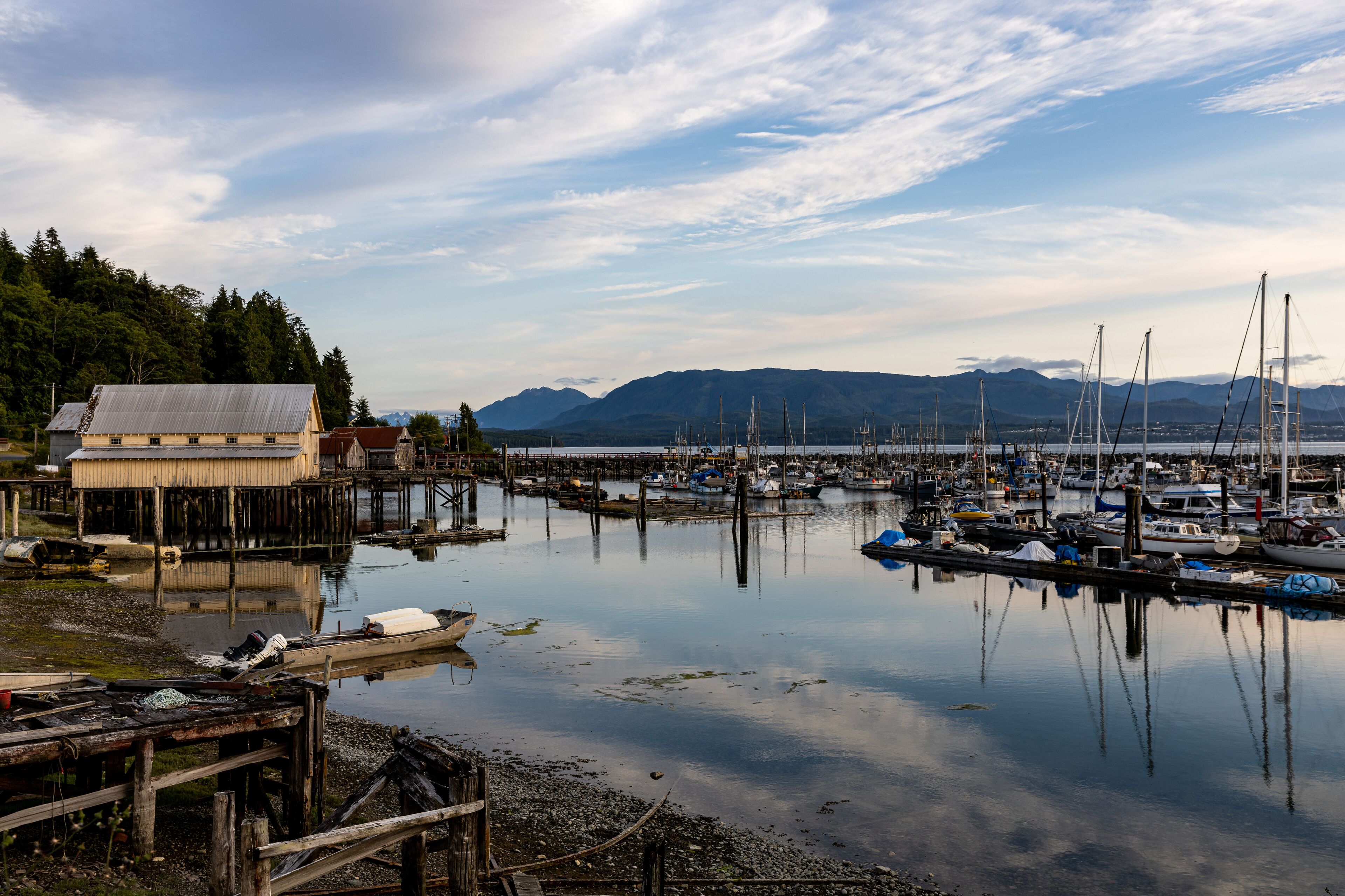 Village of Sointula, BC Canada with Vancouver Island mountains in the distance with fishing boats in the foreground as well as a net shed