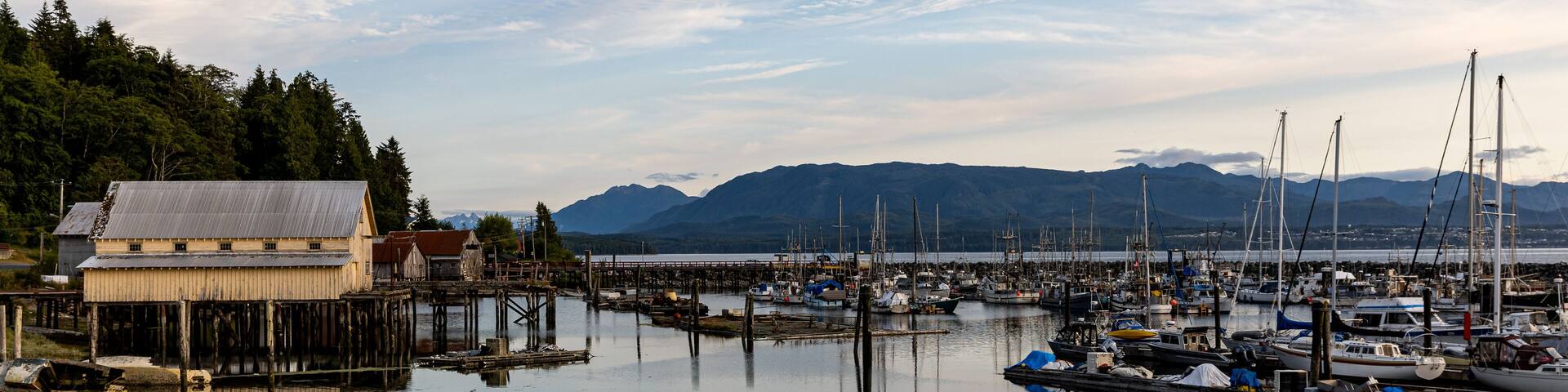 Village of Sointula, BC Canada with Vancouver Island mountains in the distance with fishing boats in the foreground as well as a net shed