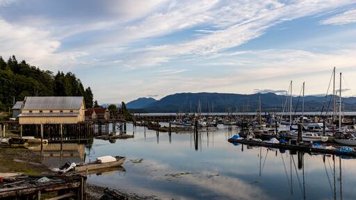 Village of Sointula, BC Canada with Vancouver Island mountains in the distance with fishing boats in the foreground as well as a net shed