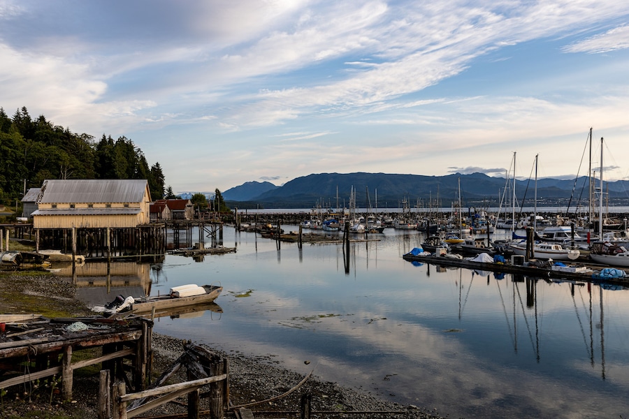 Village of Sointula, BC Canada with Vancouver Island mountains in the distance with fishing boats in the foreground as well as a net shed
