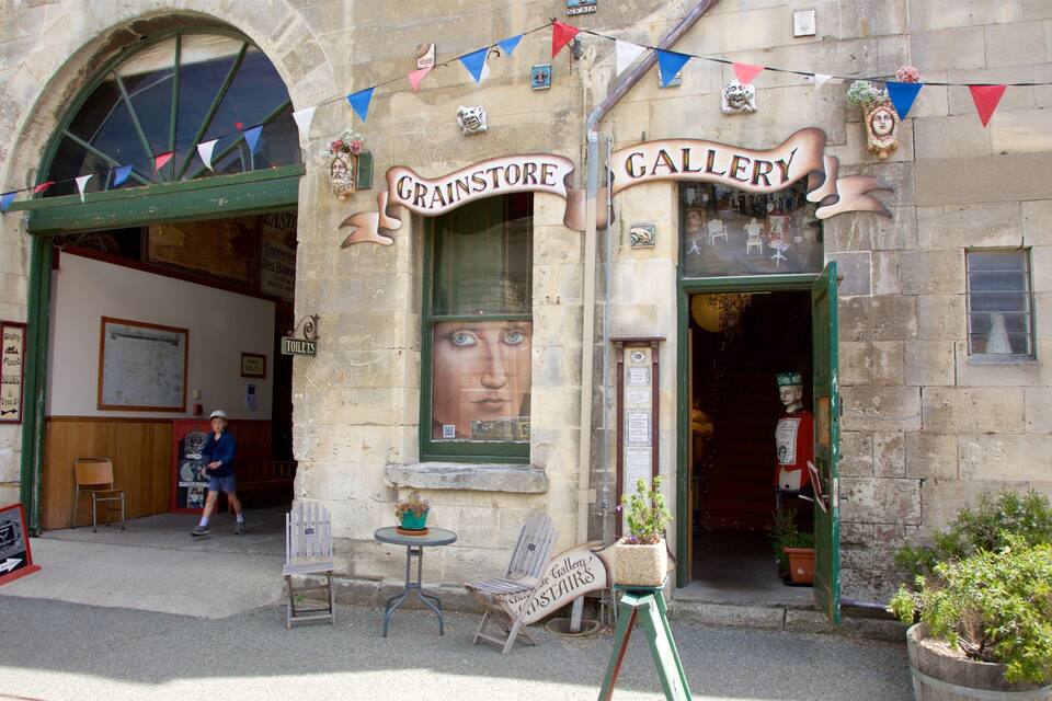 Um edifício com uma placa que diz "Grainstore Gallery" e um manequim vestido com uma coroa.