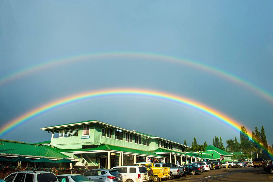 A building with a green roof and a rainbow in the sky.