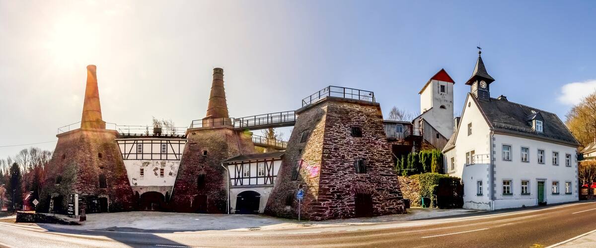 A historic building with stone towers and a white facade, a bridge, and a clock tower.