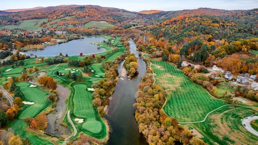 Aerial view of the Connecticut River snaking through a vibrant tapestry of fall foliage near a golf course and lake, White River Junction, Vermont, United States.