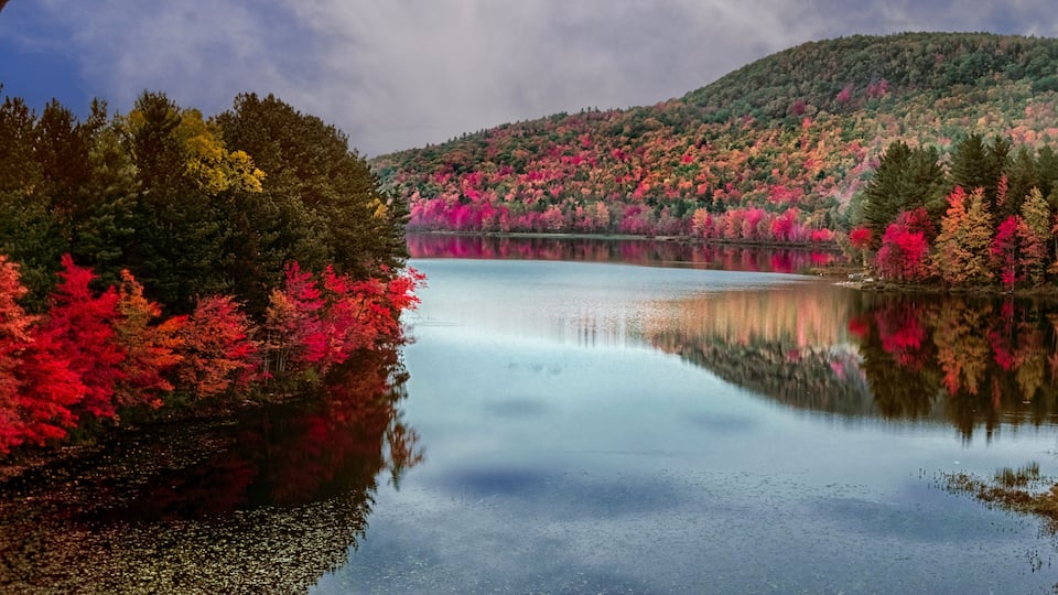 A calm lake surrounded by vibrant autumn foliage.
