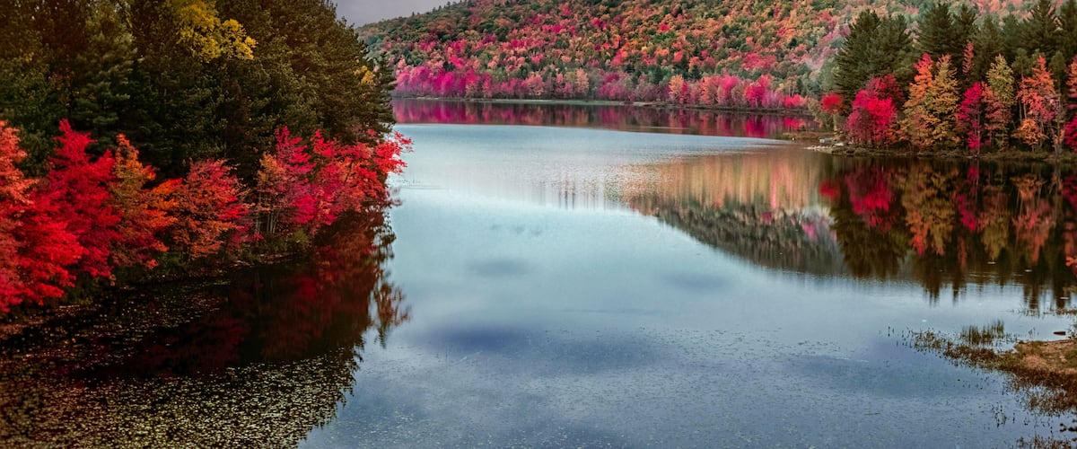 A calm lake surrounded by vibrant autumn foliage.