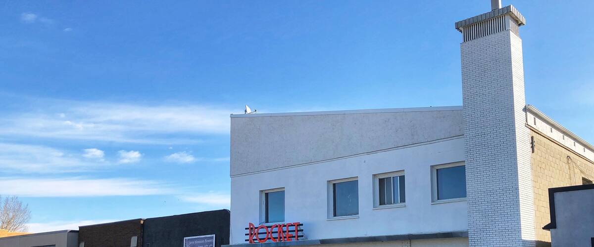 A white building with a red sign that reads "ROCKETS" and a chimney.