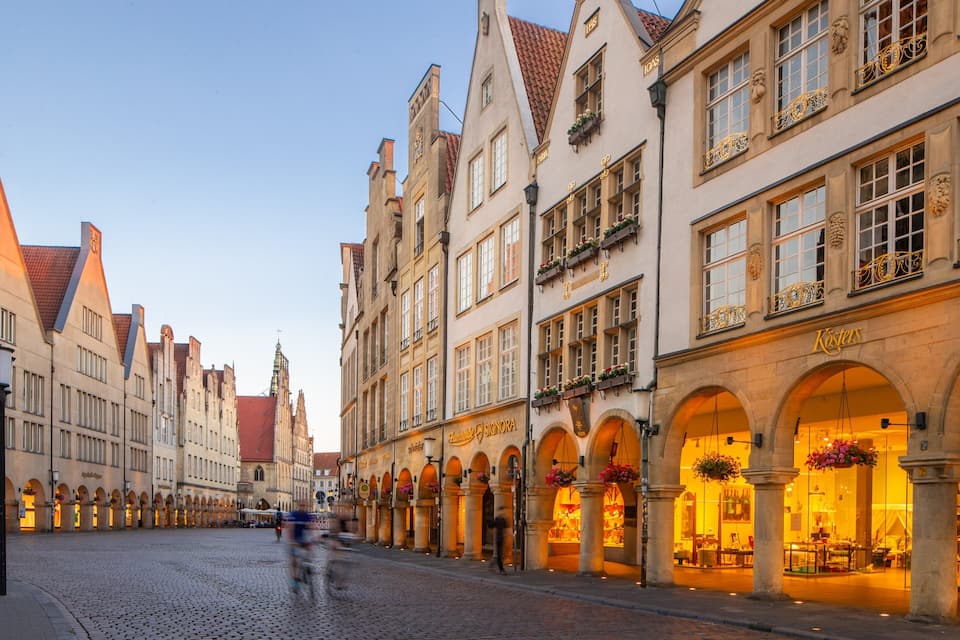 Eine Kopfsteinpflasterstraße gesäumt von historischen Gebäuden, darunter ein Geschäft mit der Aufschrift 'Kästers'.