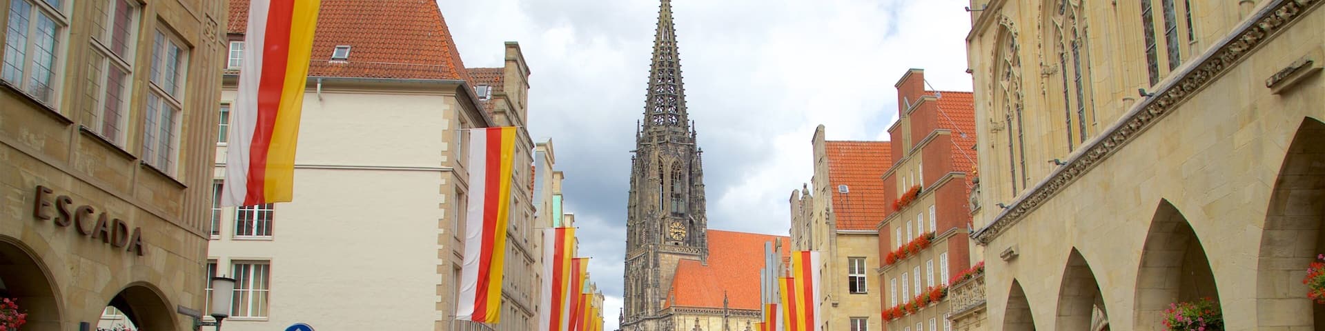 A bustling street with pedestrians and cyclists, historic buildings, and a prominent church spire.
