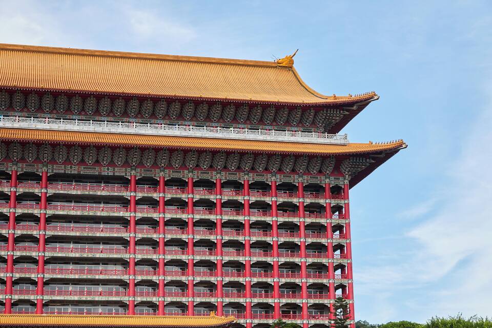 Un edifici tradicional de diversos pisos amb columnes vermelles i un teulat daurat.