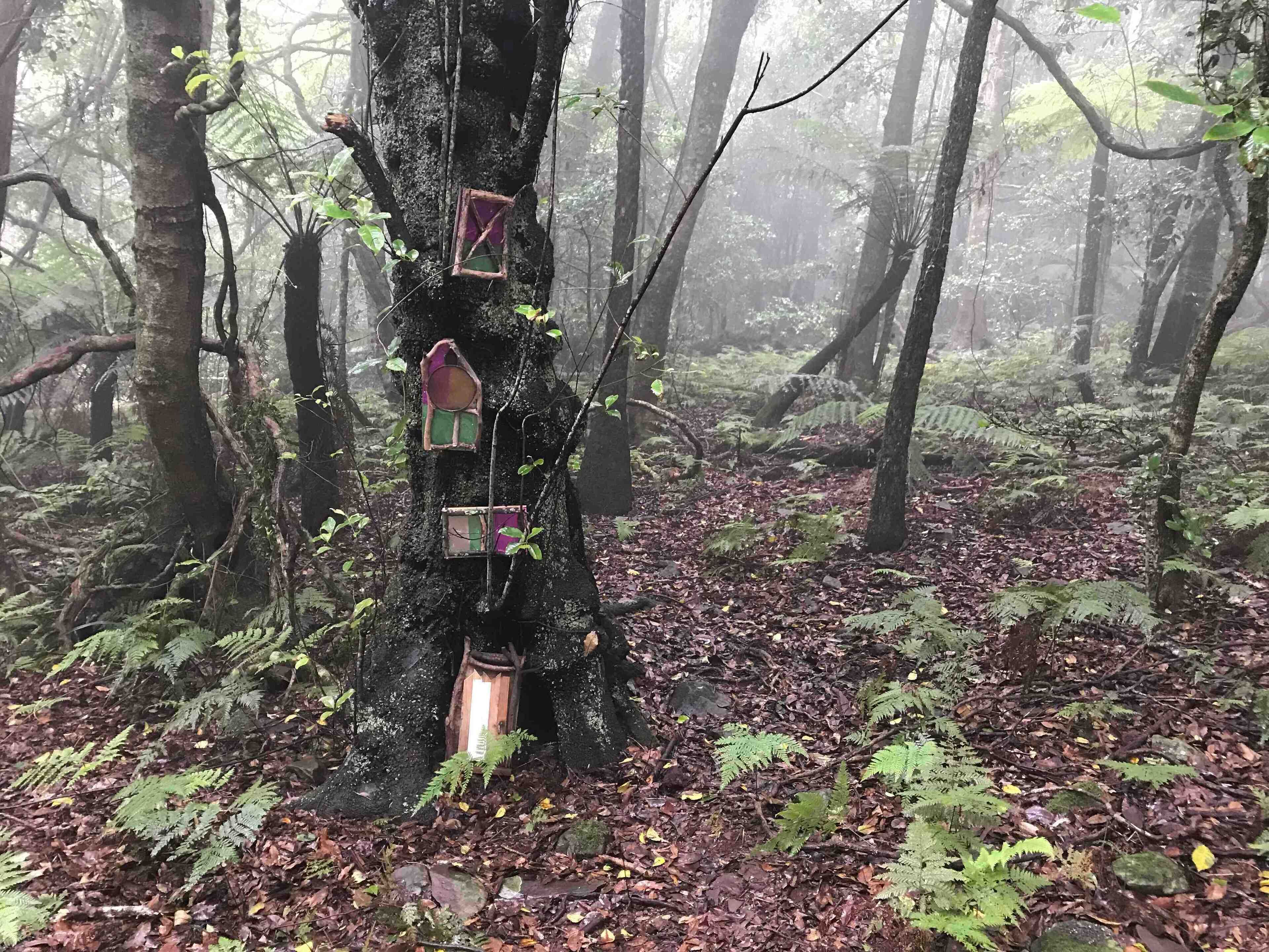 A forest with a tree decorated with colorful objects.