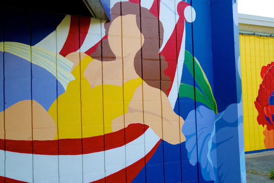A colorful mural with abstract figures and a large flower on a building.
