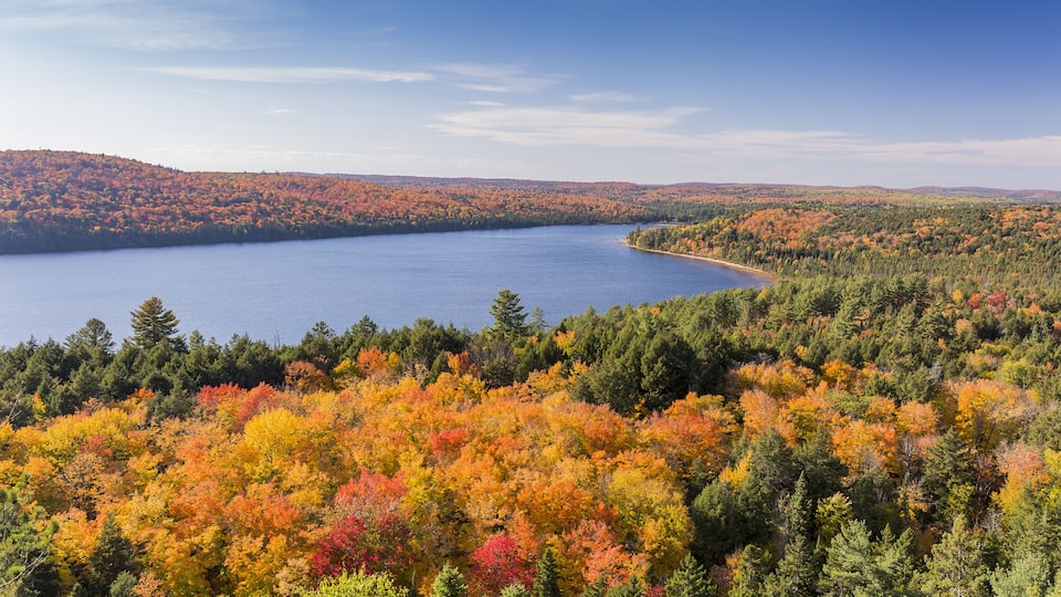 A lake surrounded by autumn-colored trees and distant hills.