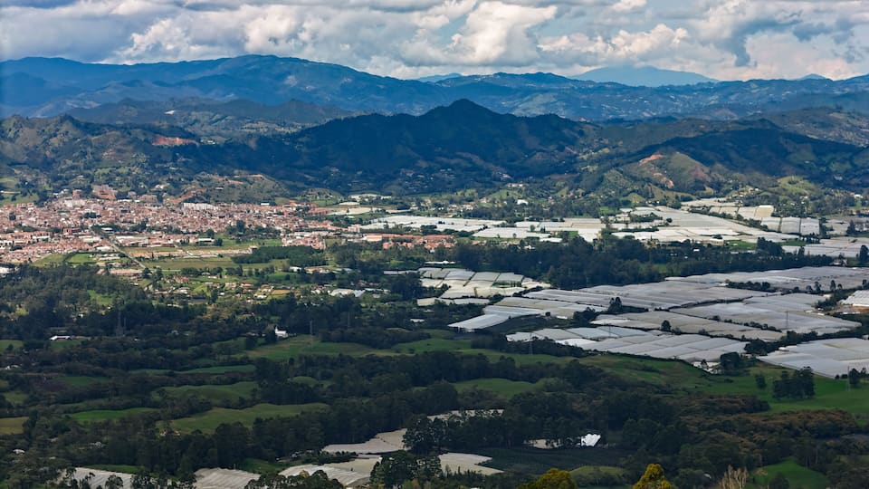 A city nestled in a valley with surrounding mountains and agricultural fields.