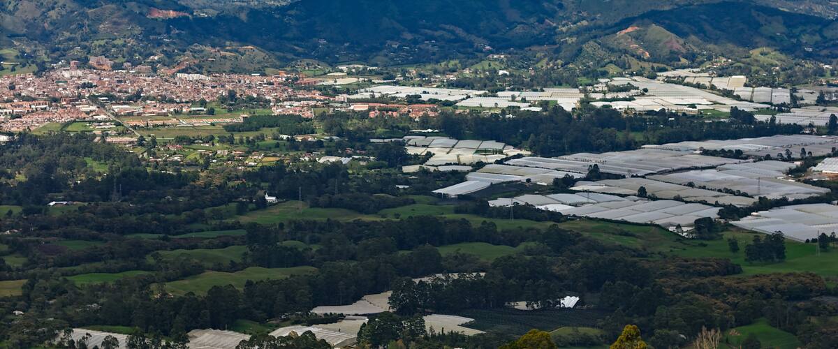 A city nestled in a valley with surrounding mountains and agricultural fields.